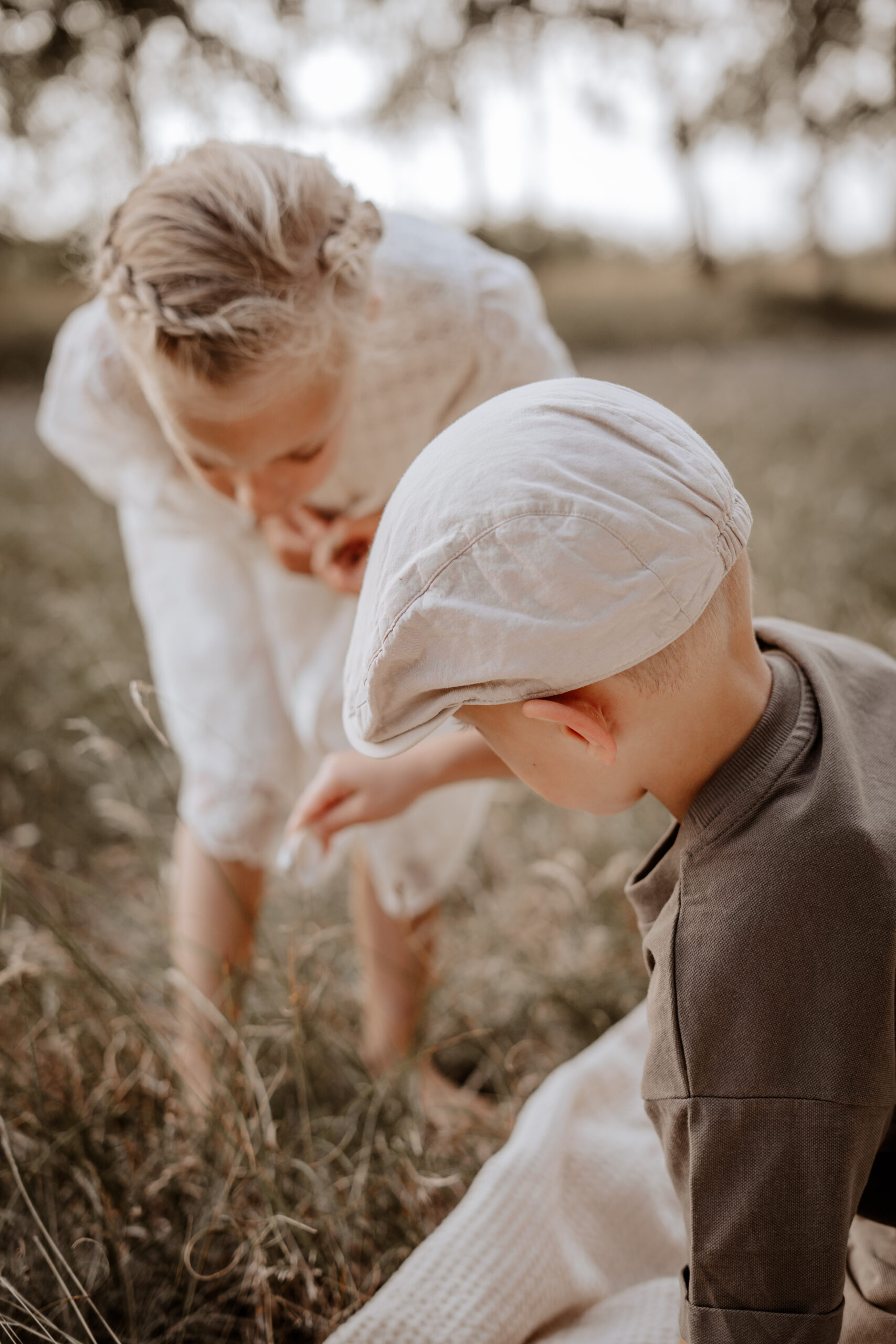 Junge und Mädchen erkunden als Zwillings-Geschwister während eines Familienshootings gemeinsam ihre Umgebung. Das Foto wird auf der Unterseite zum Ablauf eines Fotoshootings bei der Beschreibung über die fertigen Erinnerungen angezeigt.